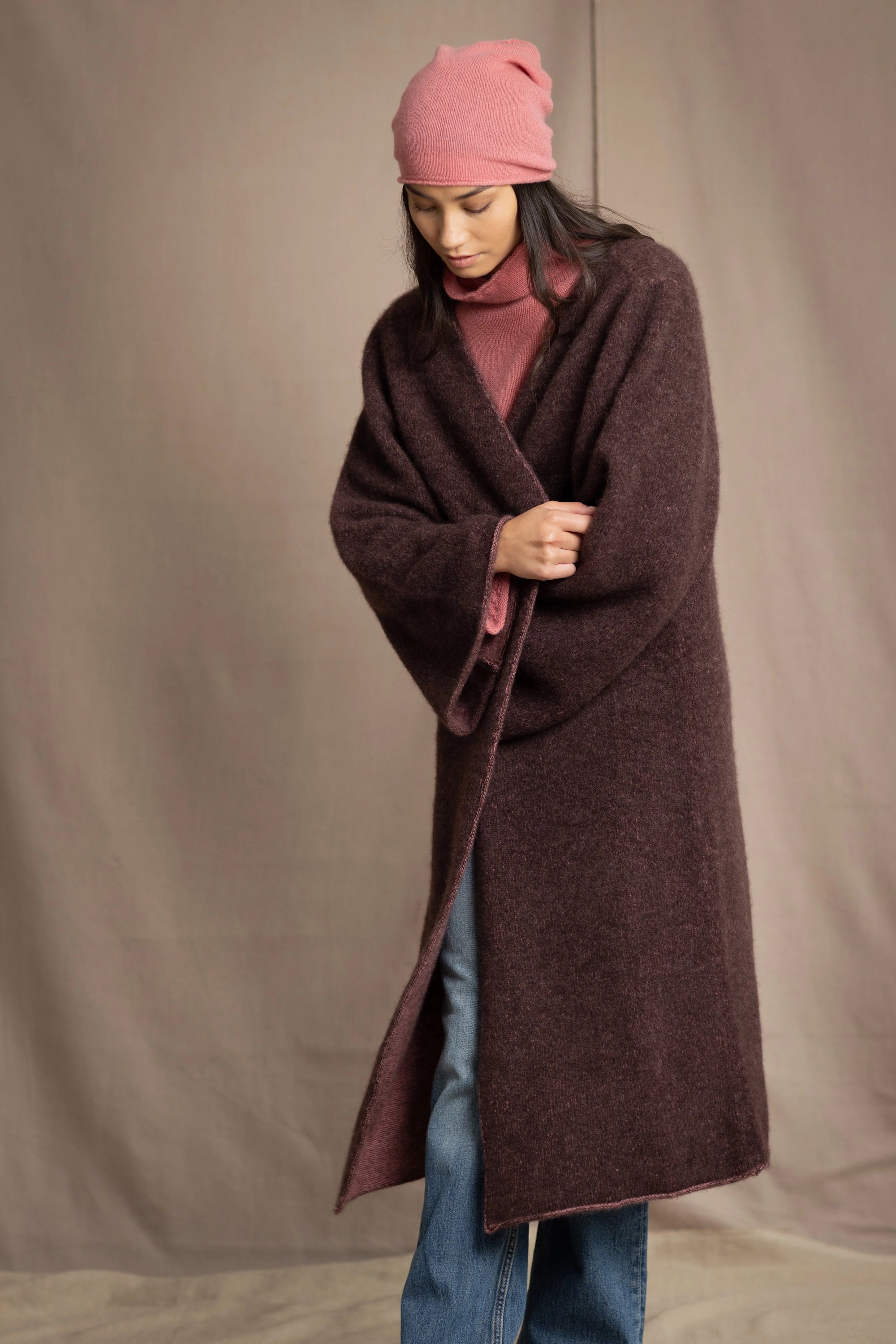 Woman wearing a long brown cashmere coat and pink cashmere beanie