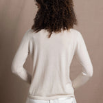 a woman wears a thin summer weight cashmere cardigan sweater in a cream colour with white silk shorts
