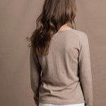 a woman wears a v neck thin summer weight cashmere sweater in a taupe colour and white jeans