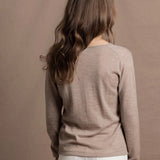 a woman wears a v neck thin summer weight cashmere sweater in a taupe colour and white jeans