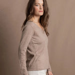 a woman wears a v neck thin summer weight cashmere sweater in a taupe colour and white jeans