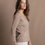 a woman wears a v neck thin summer weight cashmere sweater in a taupe colour and white jeans