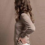 a woman wears a v neck thin summer weight cashmere sweater in a taupe colour and white jeans