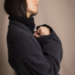 Woman wearing a long cashmere coat in dark grey over black cashmere turtleneck sweater