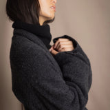 Woman wearing a long cashmere coat in dark grey over black cashmere turtleneck sweater