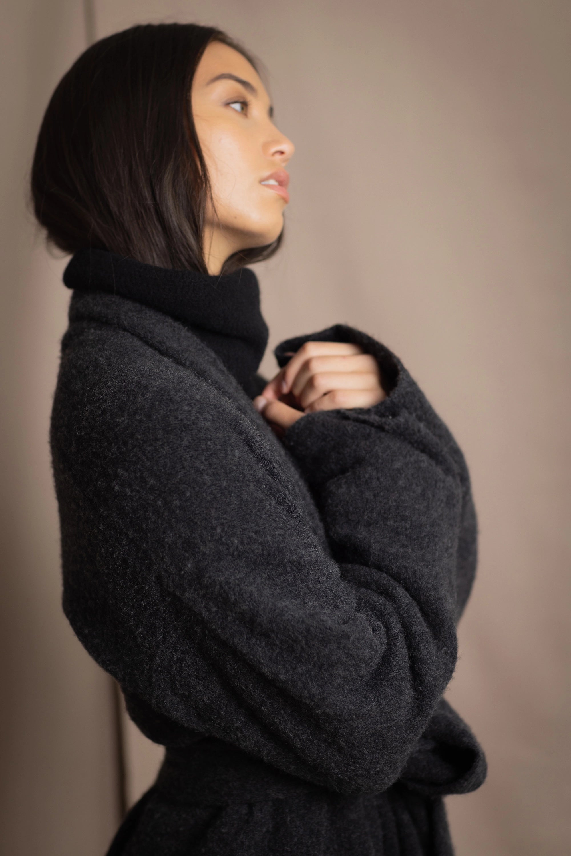 Woman wearing a long cashmere coat in dark grey over black cashmere turtleneck sweater
