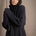 Woman wearing a long cashmere coat in dark grey over black cashmere turtleneck sweater