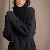 Woman wearing a long cashmere coat in dark grey over black cashmere turtleneck sweater