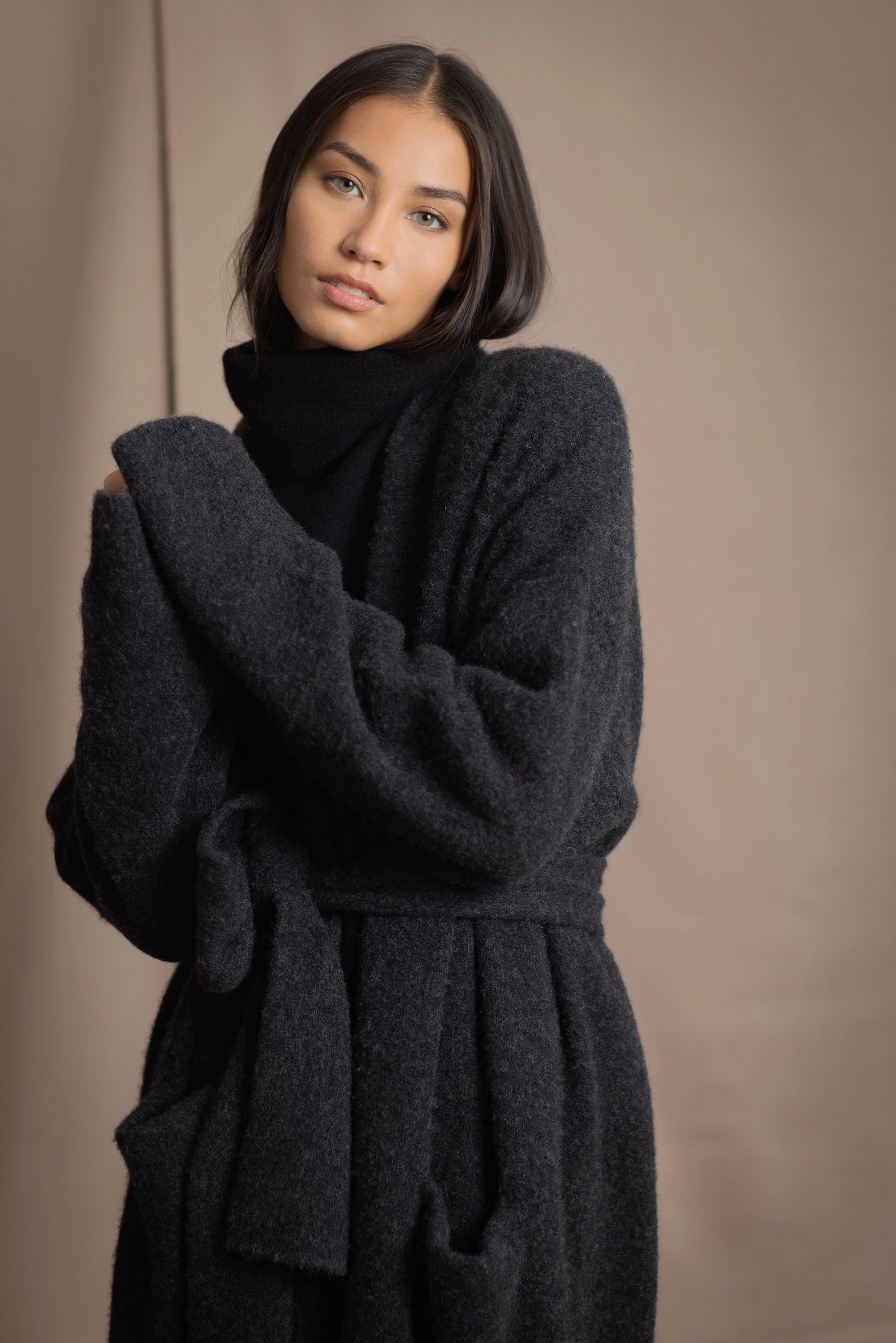 Woman wearing a long cashmere coat in dark grey over black cashmere turtleneck sweater