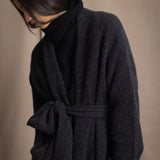 Woman wearing a long cashmere coat in dark grey over black cashmere turtleneck sweater