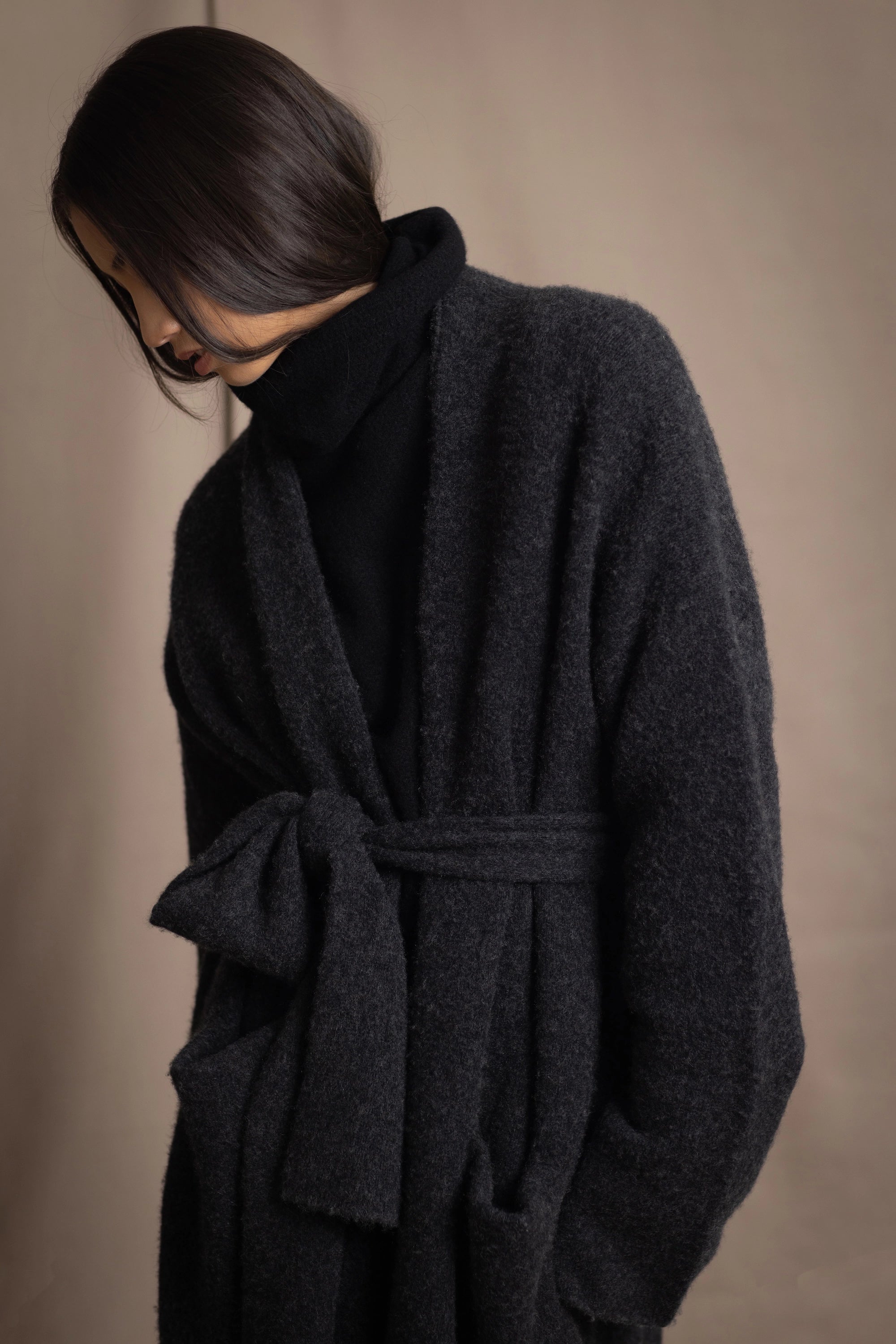 Woman wearing a long cashmere coat in dark grey over black cashmere turtleneck sweater