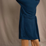Woman wearing a long cashmere coat in teal blue over teal blue cashmere turtleneck sweater and bronze silk trousers