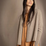 woman wearing a beige cashmere cardigan with gold metallic lurex thread over a bronze silk dress