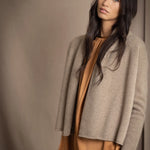 woman wearing a beige cashmere cardigan with gold metallic lurex thread over a bronze silk dress