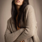woman wearing a beige cashmere cardigan with gold metallic lurex thread over a bronze silk dress