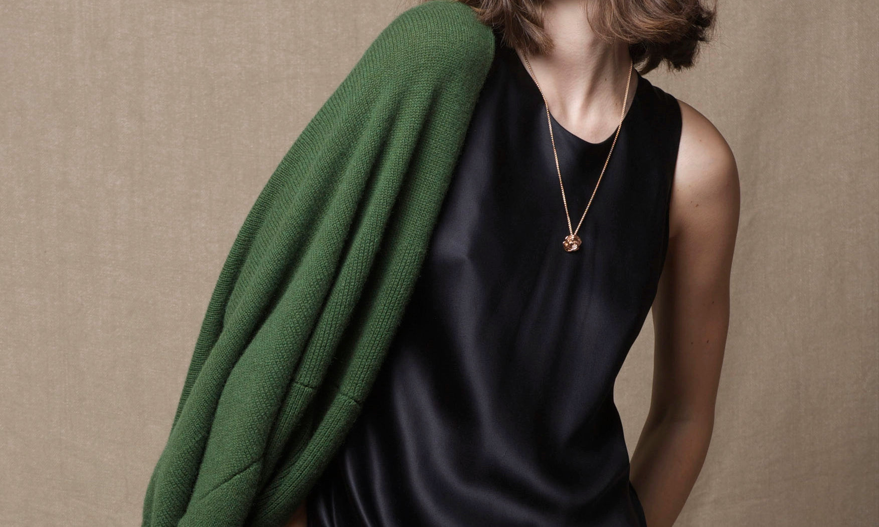 a woman stands in a black silk sleeveless dress and a large green cashmere wrap over her shoulders