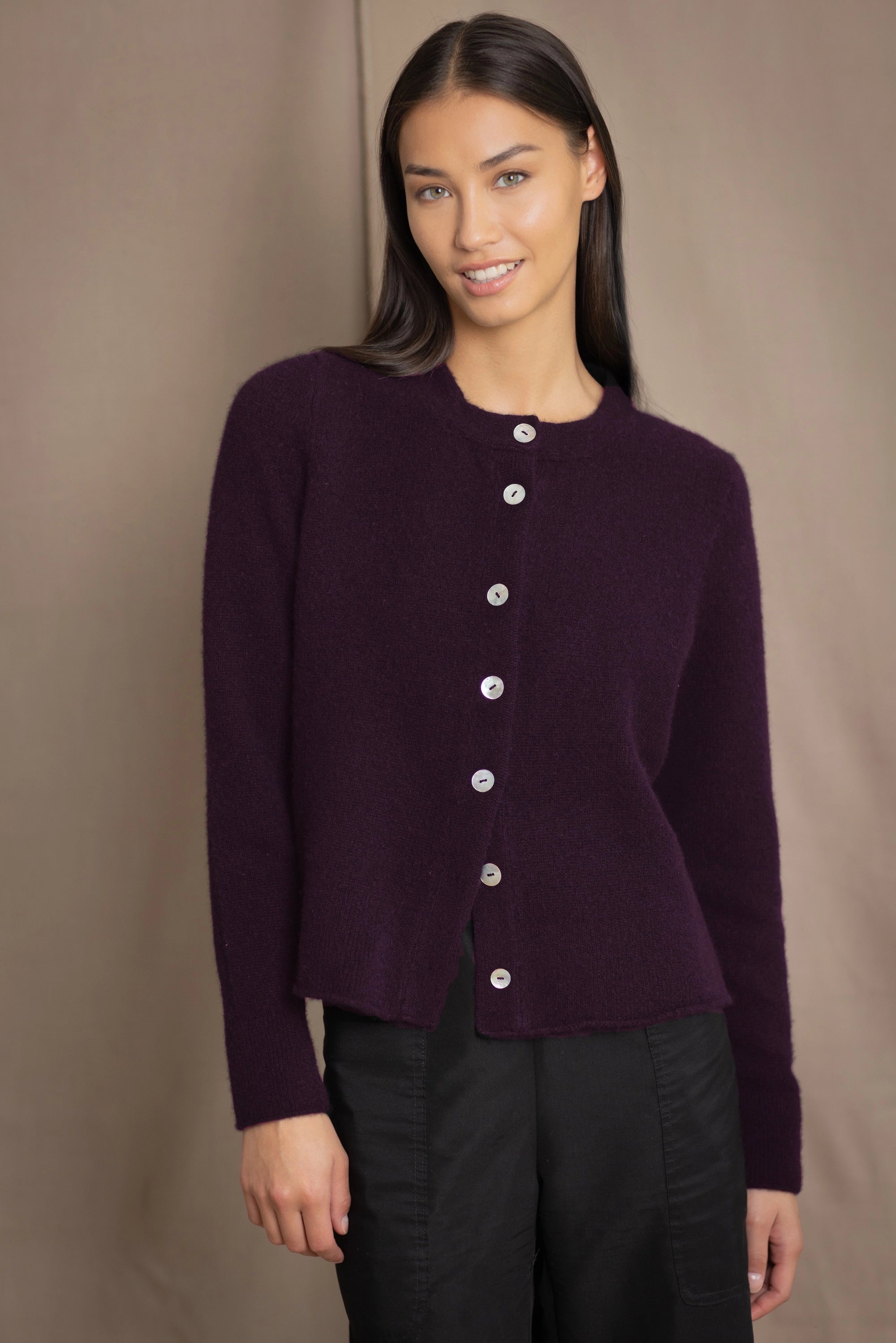 Woman wearing a dark purple cashmere cardigan with mother of pearl buttons