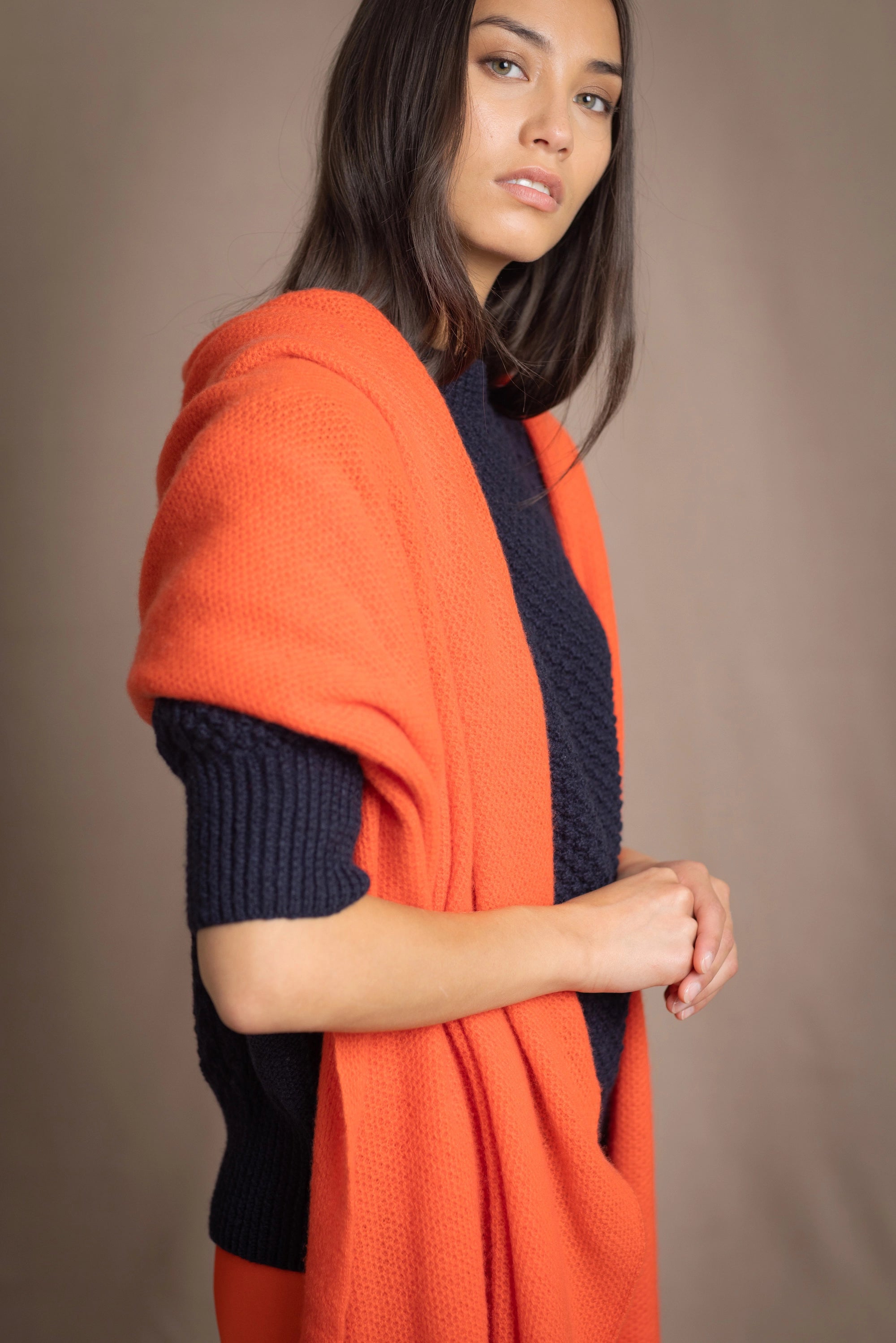 a woman wears an extra large cashmere wrap shawl in bright orange