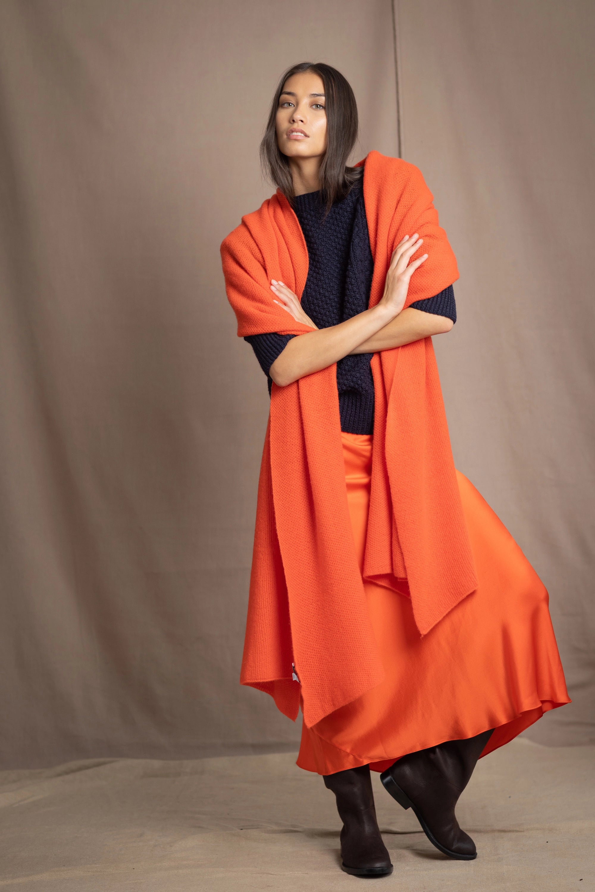 a woman wears an extra large cashmere wrap shawl in bright orange