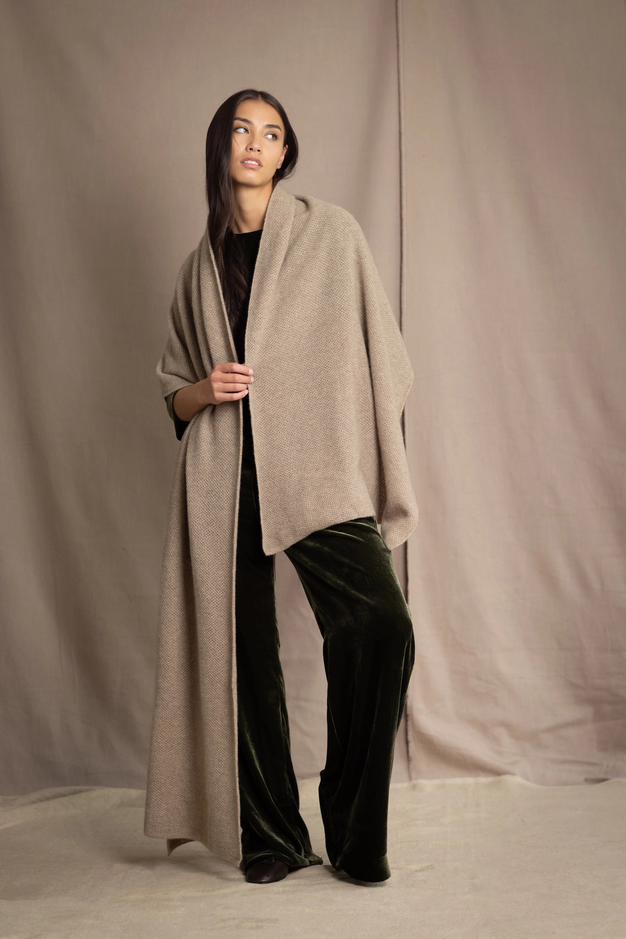 Woman wearing a beige and metallic gold cashmere blanket wrap over green silk velvet clothing