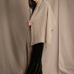 Woman wearing a beige and metallic gold cashmere blanket wrap over green silk velvet clothing