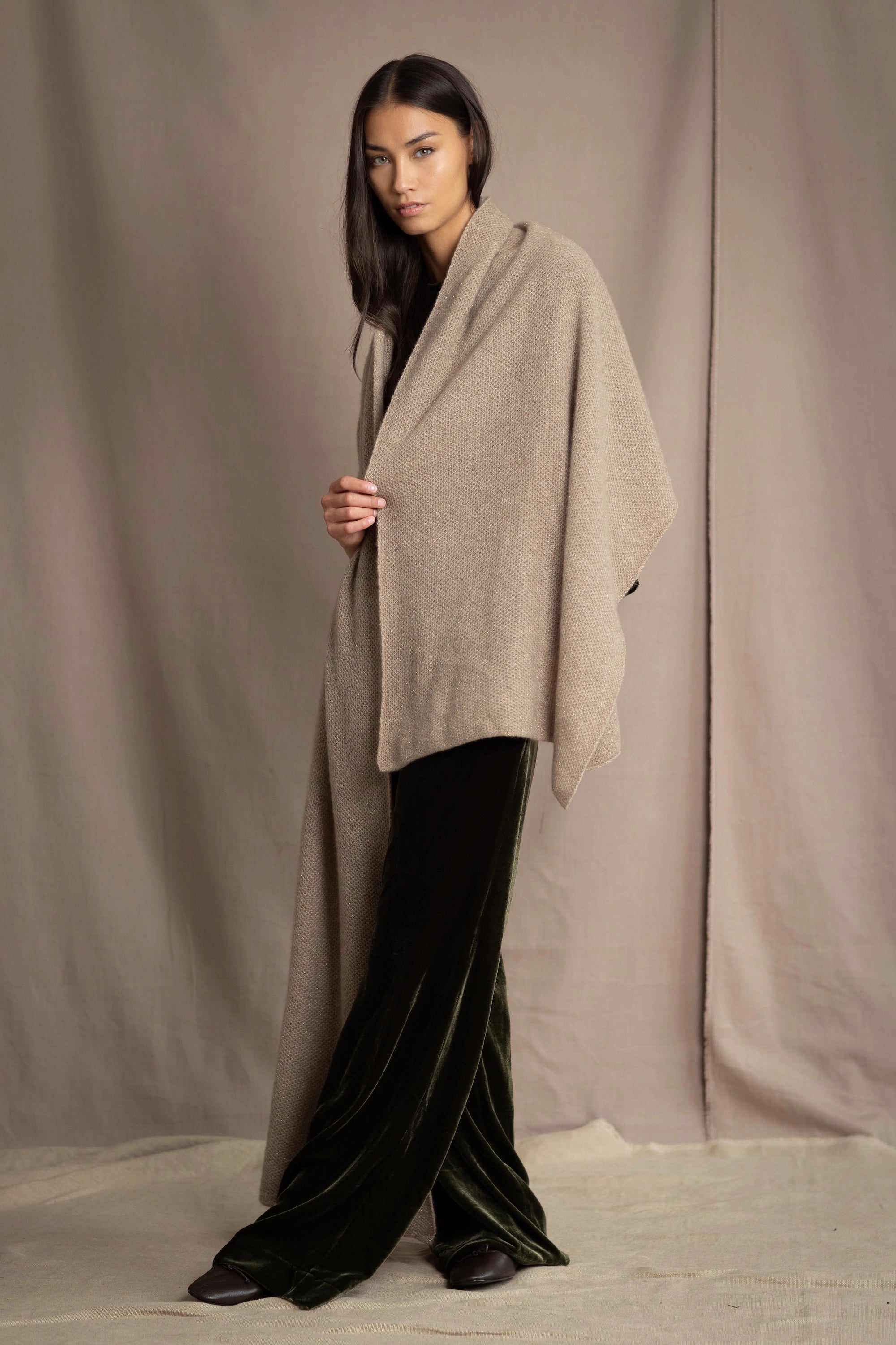 Woman wearing a beige and metallic gold cashmere blanket wrap over green silk velvet clothing