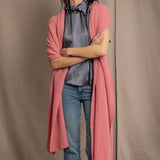 Woman wearing a cashmere blanket wrap in a dusty pink rose colour over pewter silk blouse and jeans