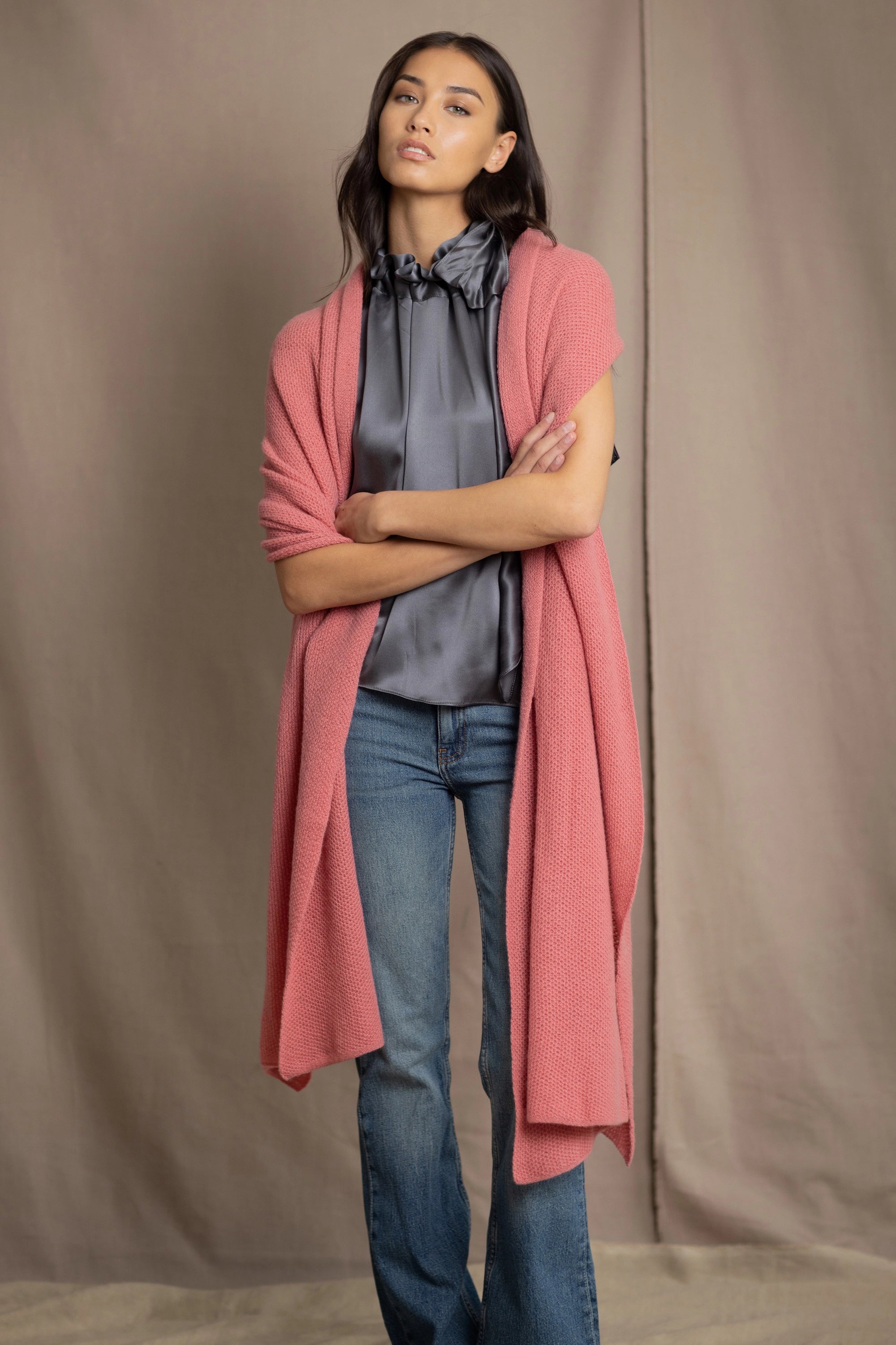 Woman wearing a cashmere blanket wrap in a dusty pink rose colour over pewter silk blouse and jeans