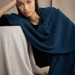 Woman wearing a teal blue cashmere blanket wrap over black silk velvet clothing