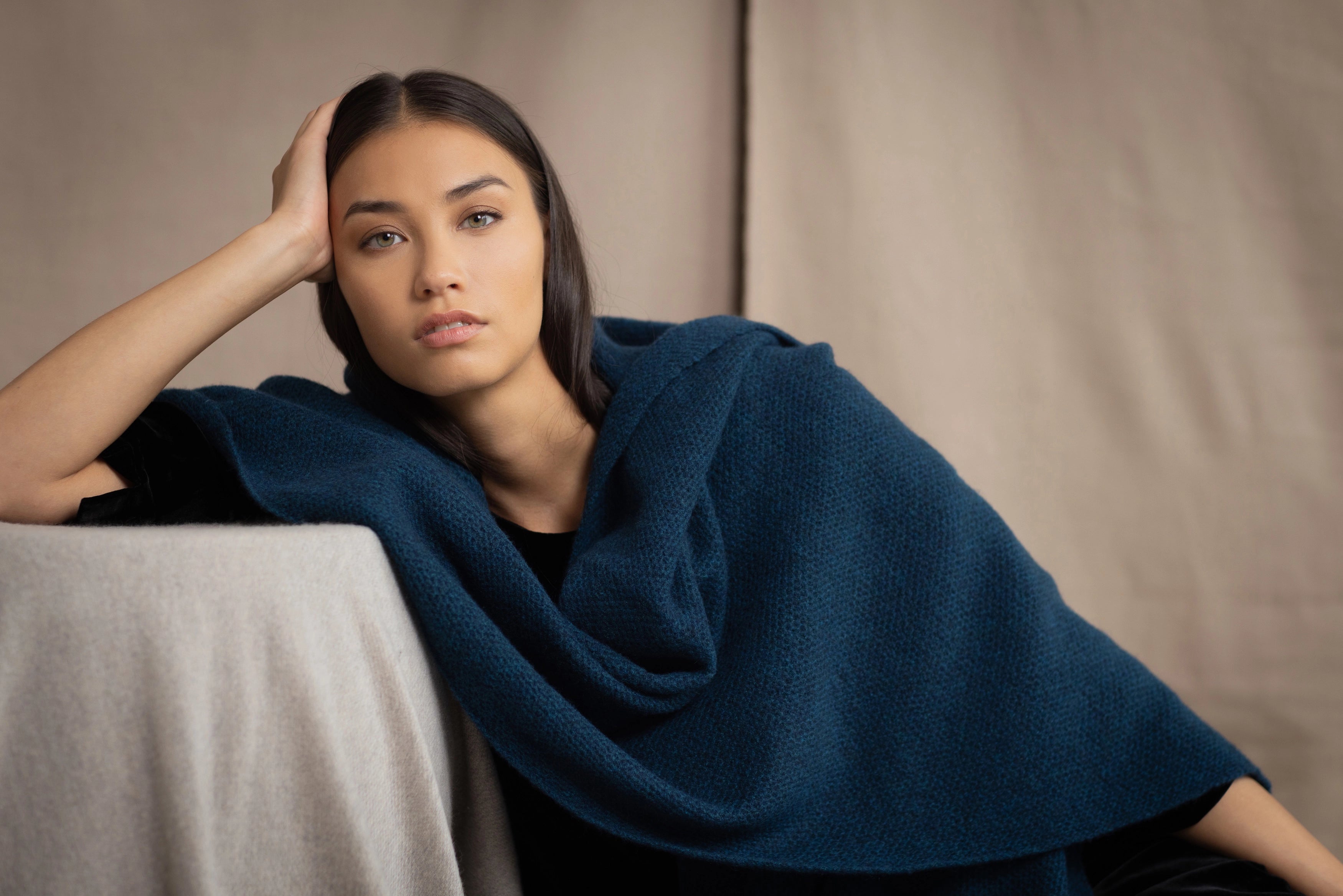 Woman wearing a teal blue cashmere blanket wrap over black silk velvet clothing