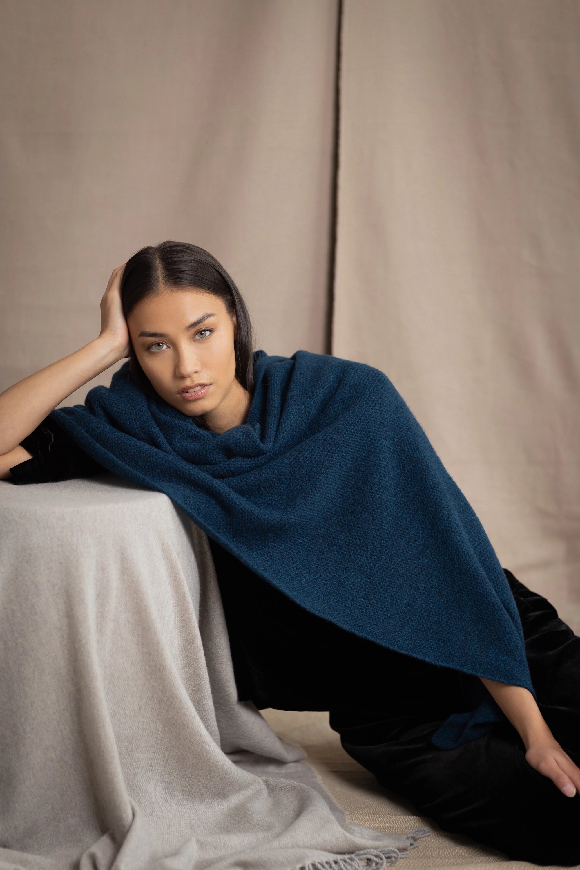 Woman wearing a teal blue cashmere blanket wrap over black silk velvet clothing
