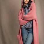 Woman wearing a long cashmere coat in dusty rose pink over a  pewter gray silk top and blue jeans