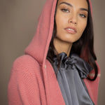 Woman wearing a long cashmere coat in dusty rose pink over a  pewter gray silk top and blue jeans
