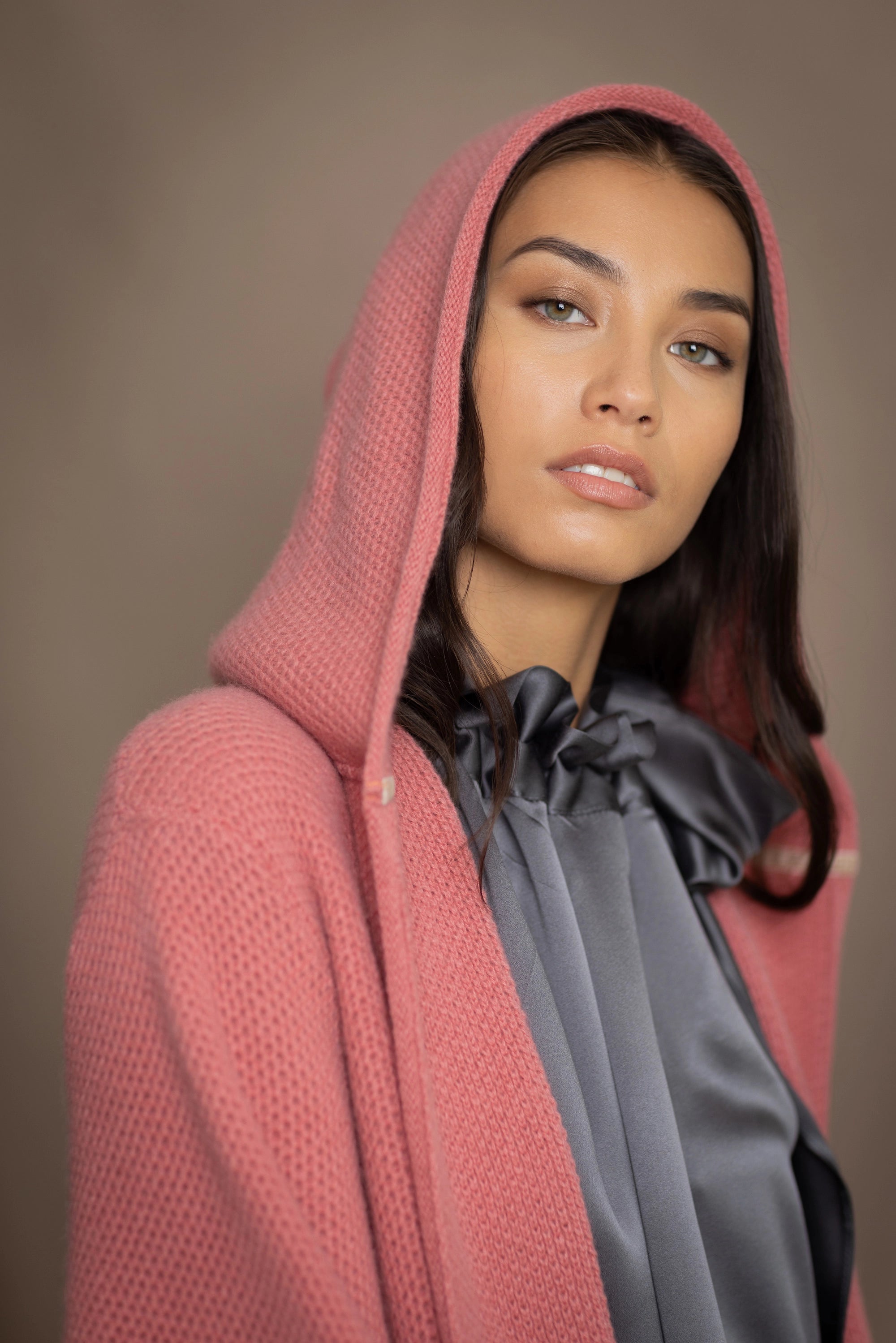 Woman wearing a long cashmere coat in dusty rose pink over a  pewter gray silk top and blue jeans