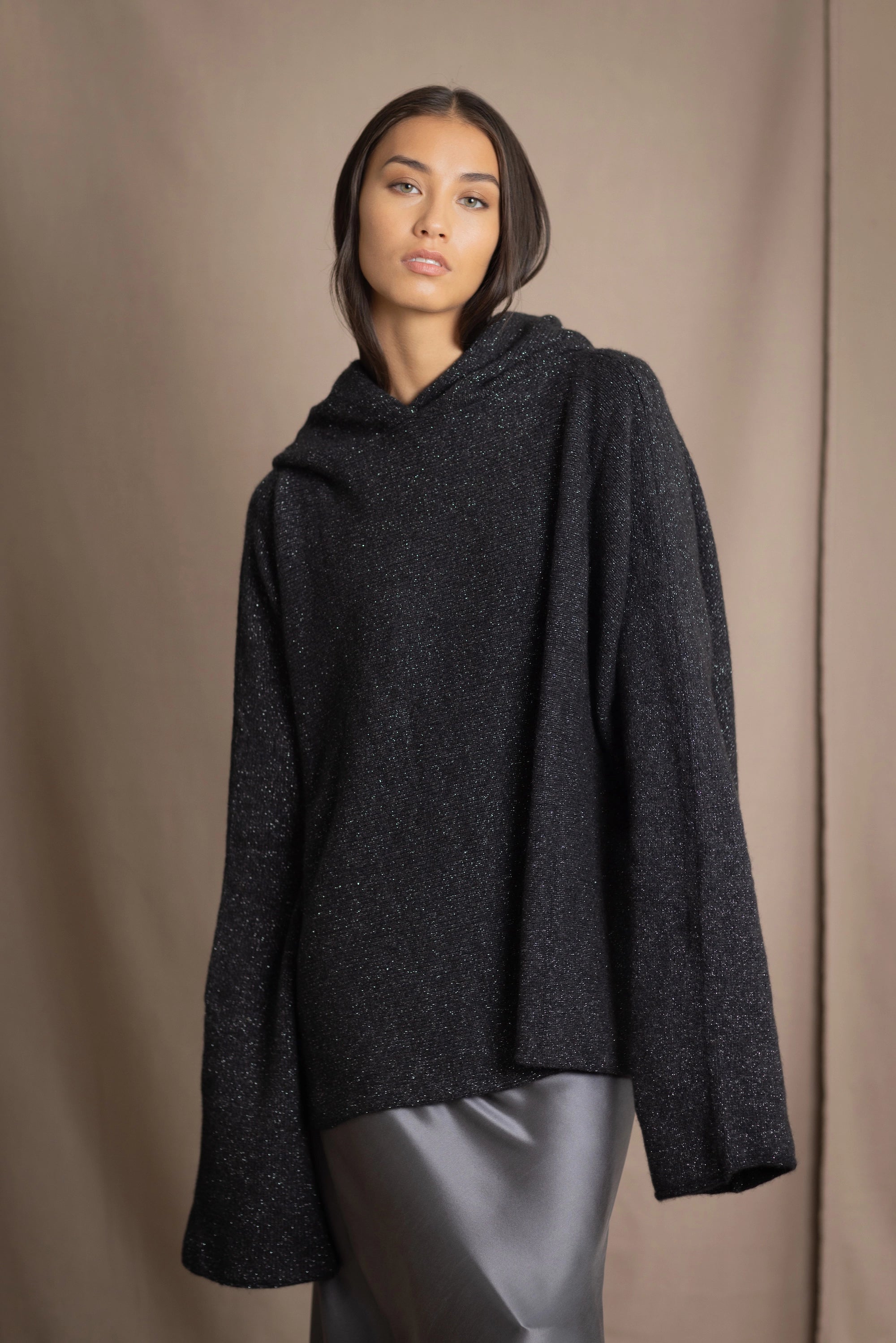 woman wearing an oversized cashmere sweater with hood in black and silver sparkly metallic colour