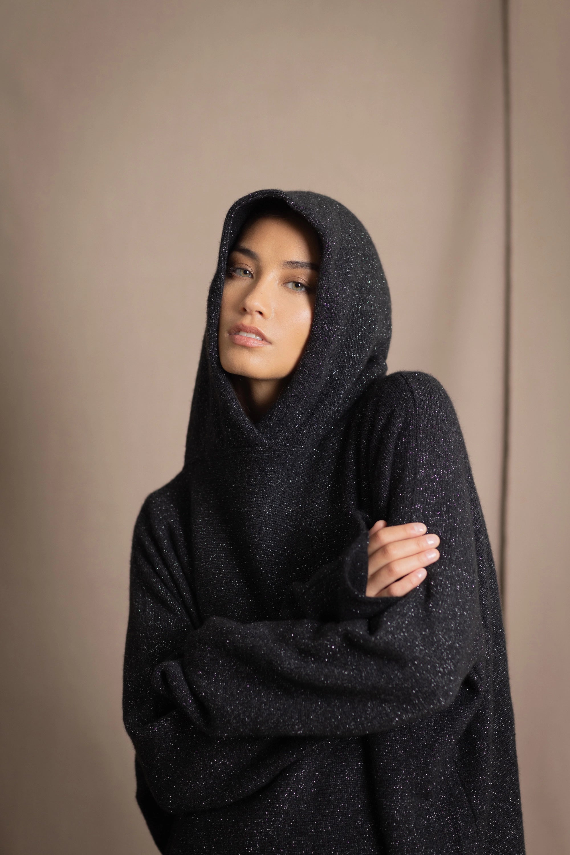 woman wearing an oversized cashmere sweater with hood in black and silver sparkly metallic colour