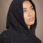 woman wearing an oversized cashmere sweater with hood in black and silver sparkly metallic colour