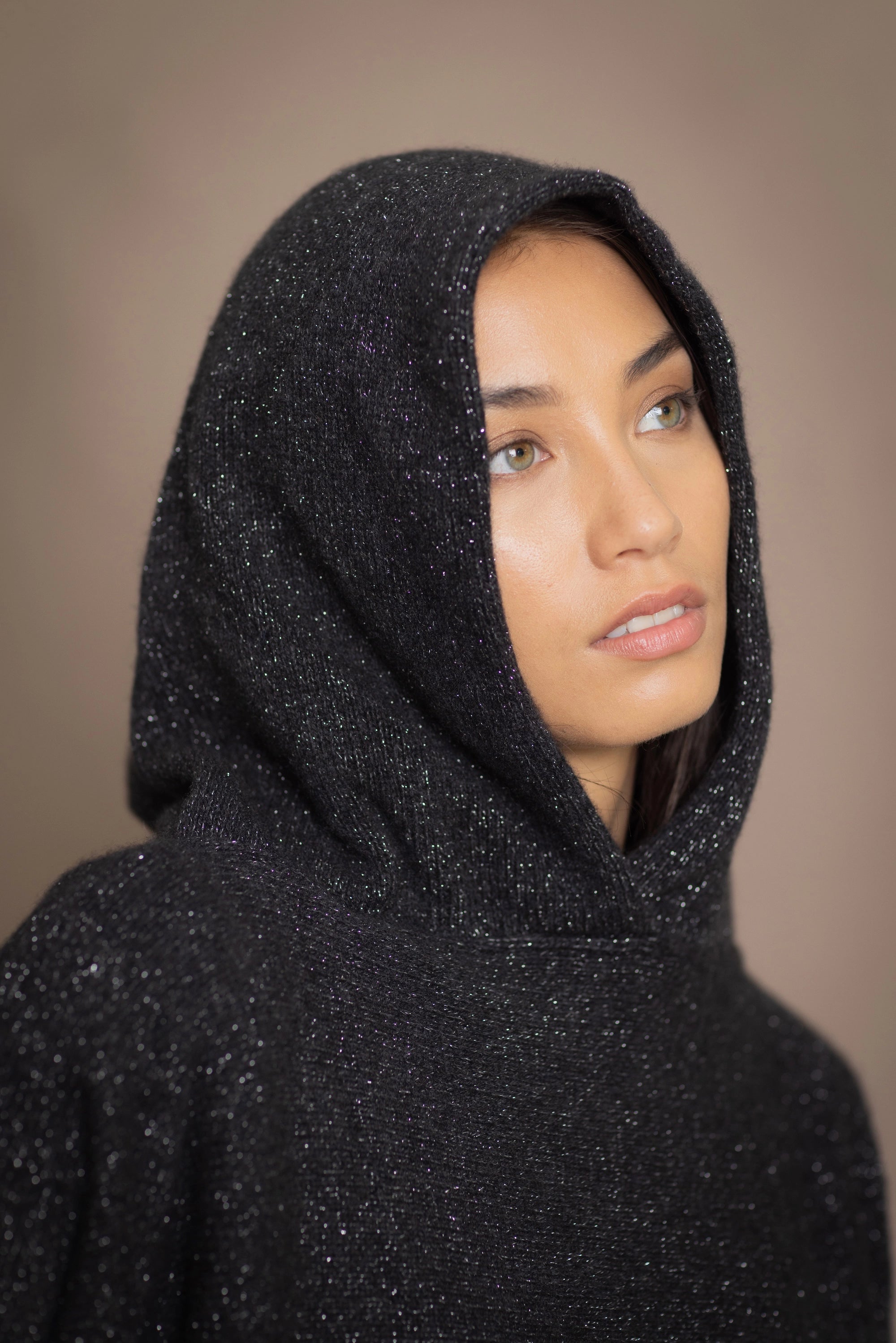 woman wearing an oversized cashmere sweater with hood in black and silver sparkly metallic colour