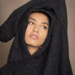 woman wearing an oversized cashmere sweater with hood in black and silver sparkly metallic colour
