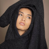 woman wearing an oversized cashmere sweater with hood in black and silver sparkly metallic colour