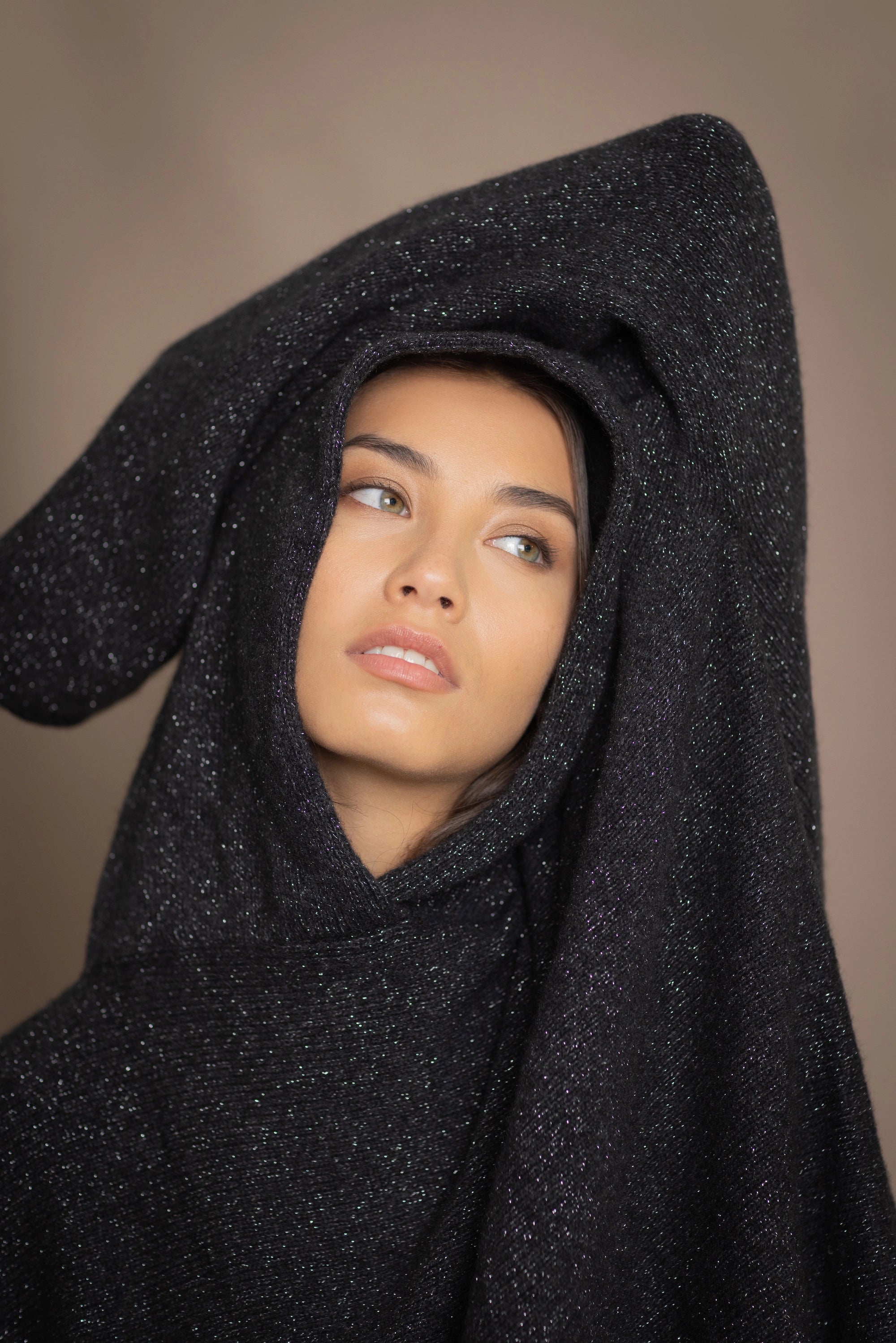 woman wearing an oversized cashmere sweater with hood in black and silver sparkly metallic colour