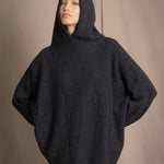 woman wearing an oversized cashmere sweater with hood in black and silver sparkly metallic colour and dark grey skirt