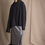 woman wearing an oversized cashmere sweater with hood in black and silver sparkly metallic colour with dark grey silk skirt and black leather boots