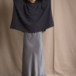 woman wearing an oversized cashmere sweater with hood in black and silver sparkly metallic colour with dark grey silk skirt and black leather boots