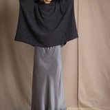 woman wearing an oversized cashmere sweater with hood in black and silver sparkly metallic colour with dark grey silk skirt and black leather boots