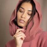 a woman wearing a cashmere snood in dusty rose pink over a matching cropped sweater