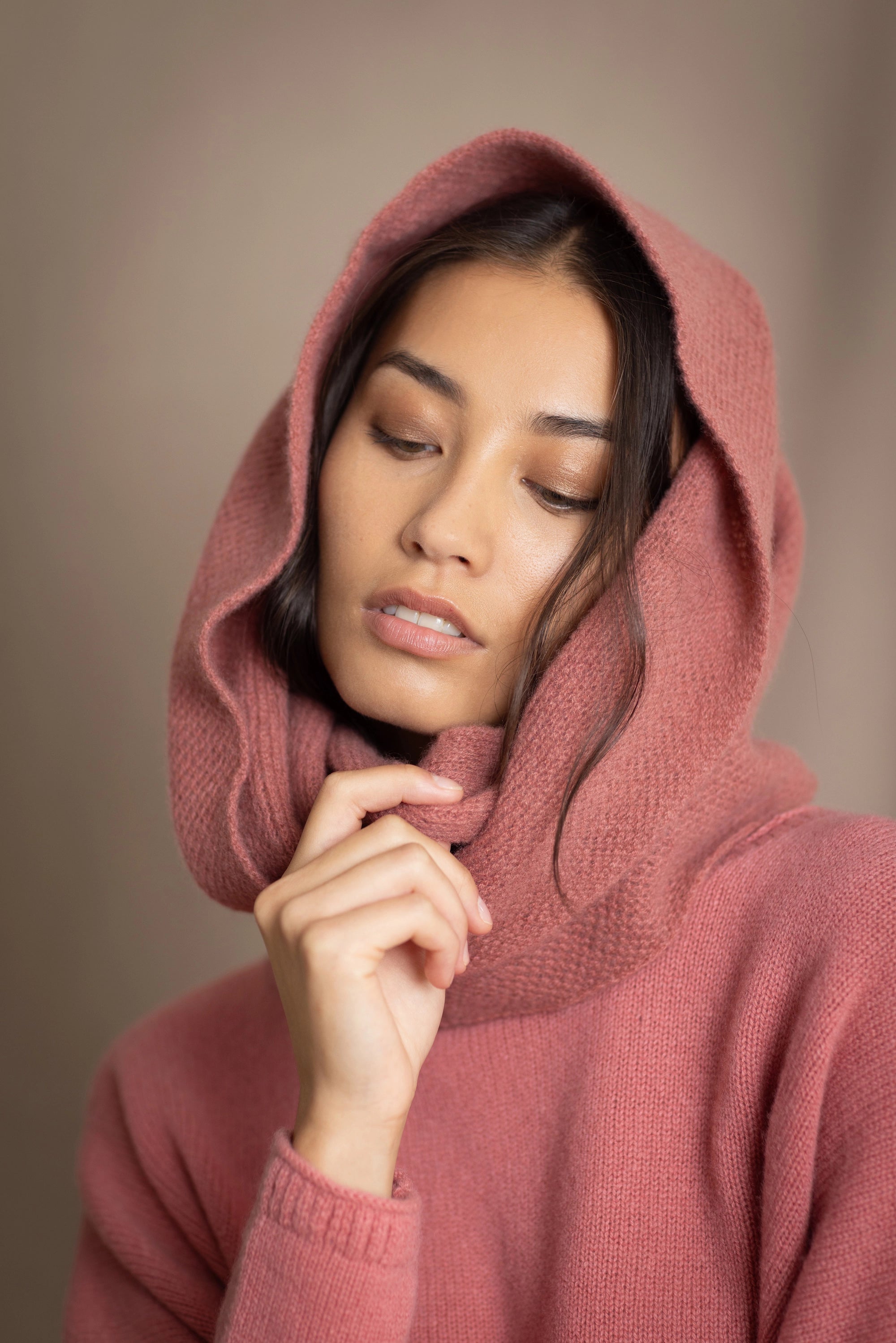 a woman wearing a cashmere snood in dusty rose pink over a matching cropped sweater
