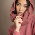 a woman wearing a cashmere snood in dusty rose pink over a matching cropped sweater