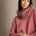 a woman wearing a cropped cashmere oversized cashmere sweater in dusty rose pink with matching cashmere snood over silk trousers in pewter grey