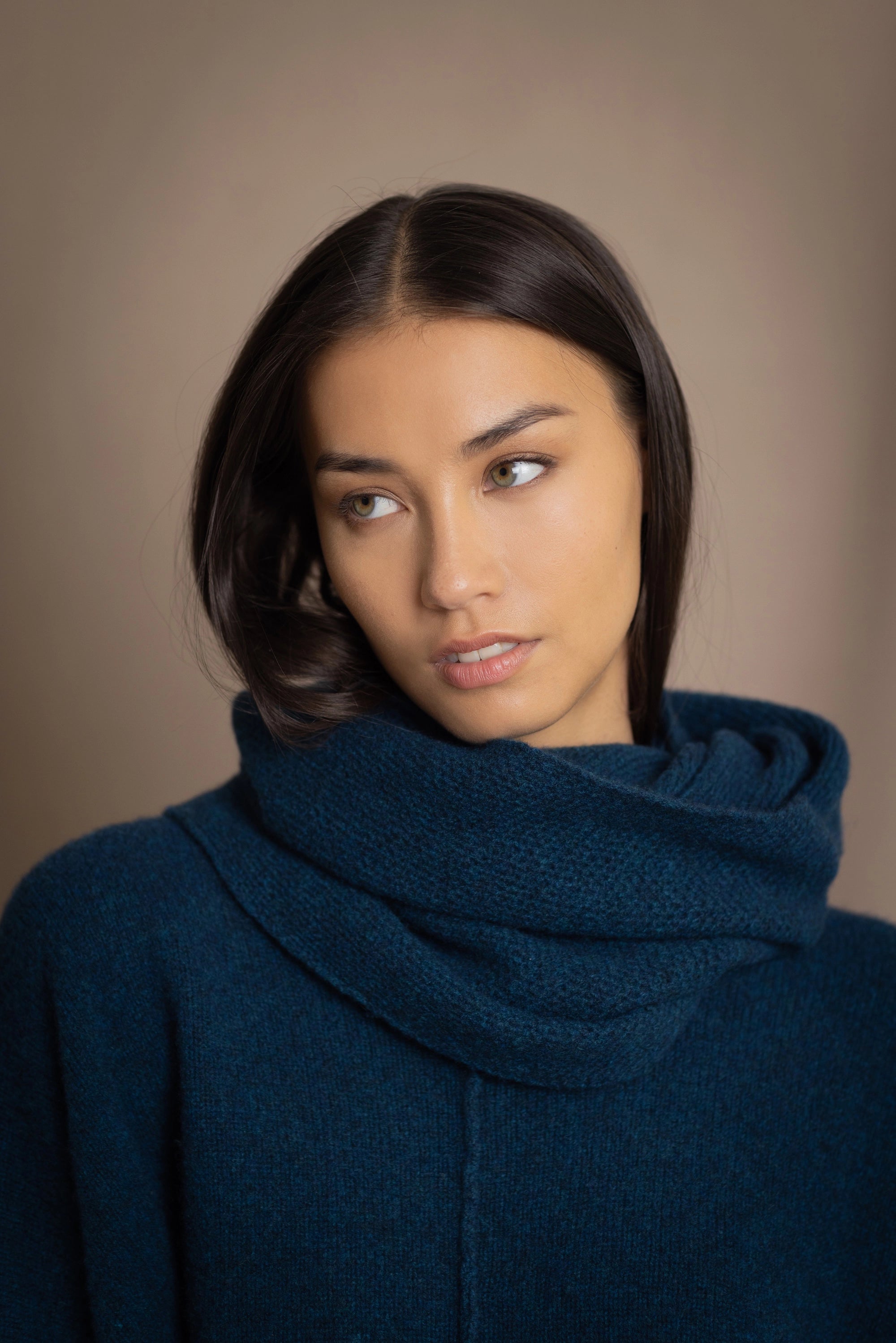 a woman wearing a cashmere snood in teal over cashmere sweater in teal